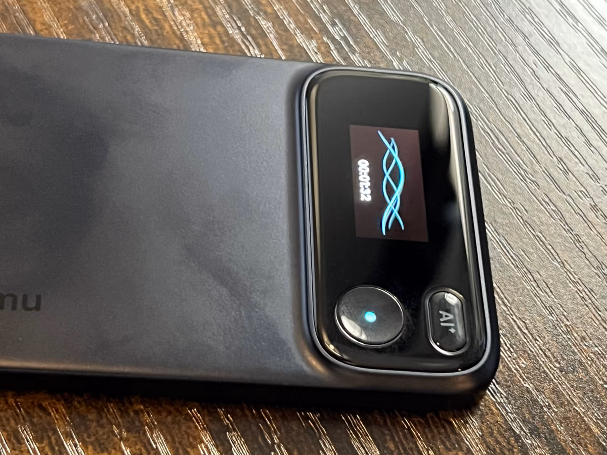 Close-up of the Comu Action Pro screen showing a recording waveform, with the AI button beside it.